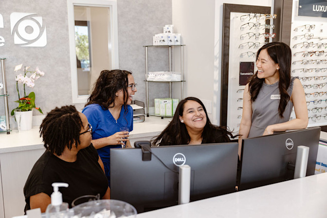Eye care office staff laughing with optometrist